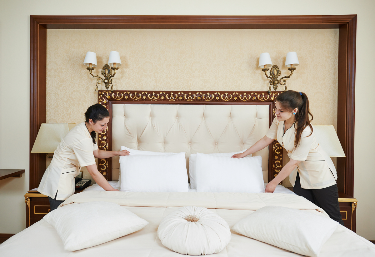 Housekeeper menata sprei rapi di kamar hotel