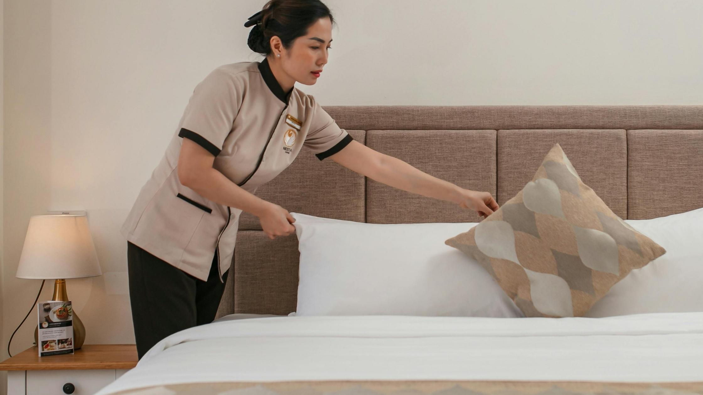 Staf hotel merapikan tempat tidur