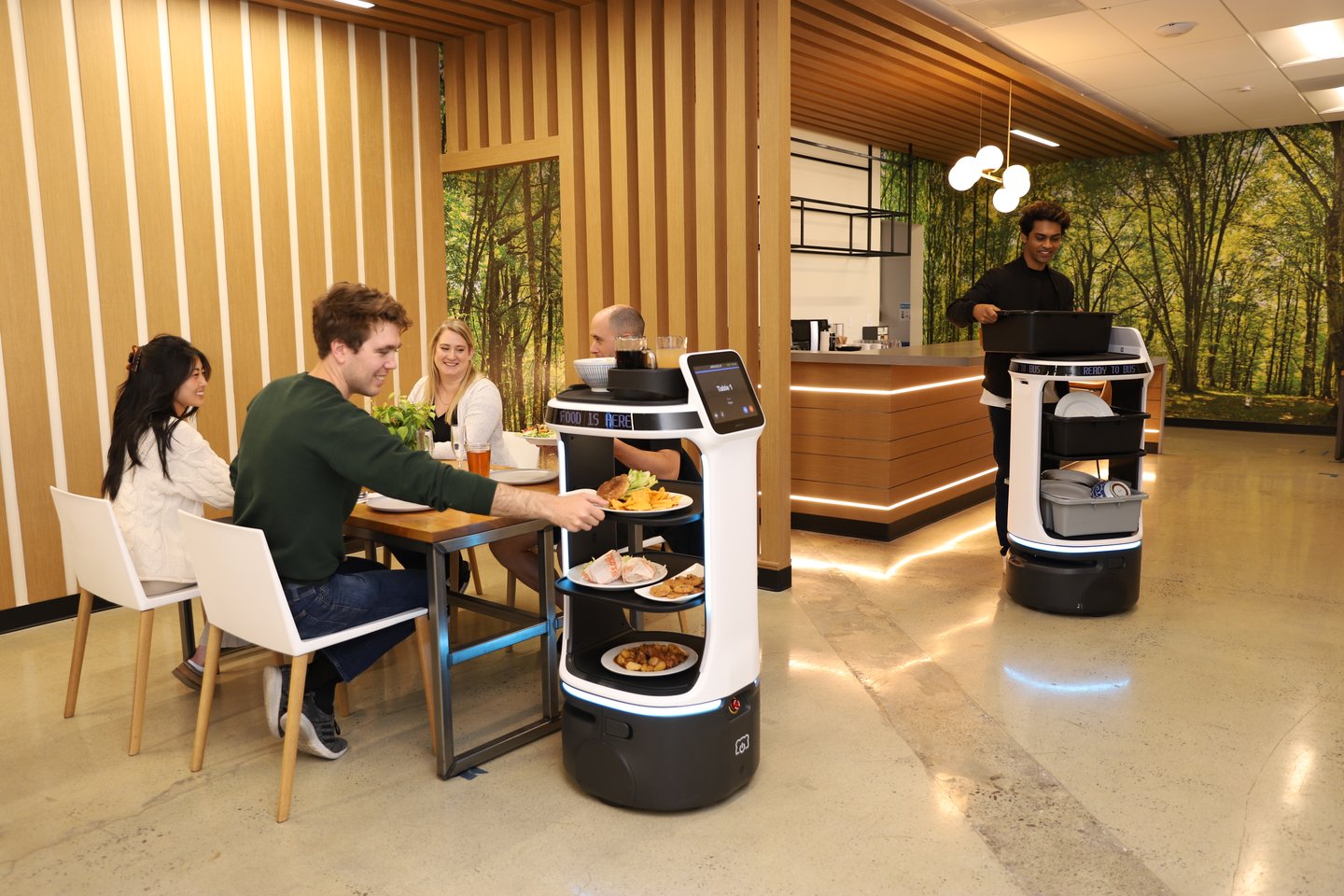 Robot pelayan sedang mengantar makanan di lobi hotel.
