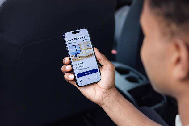 Businessman is booking a hotel room on a mobile phone in a car