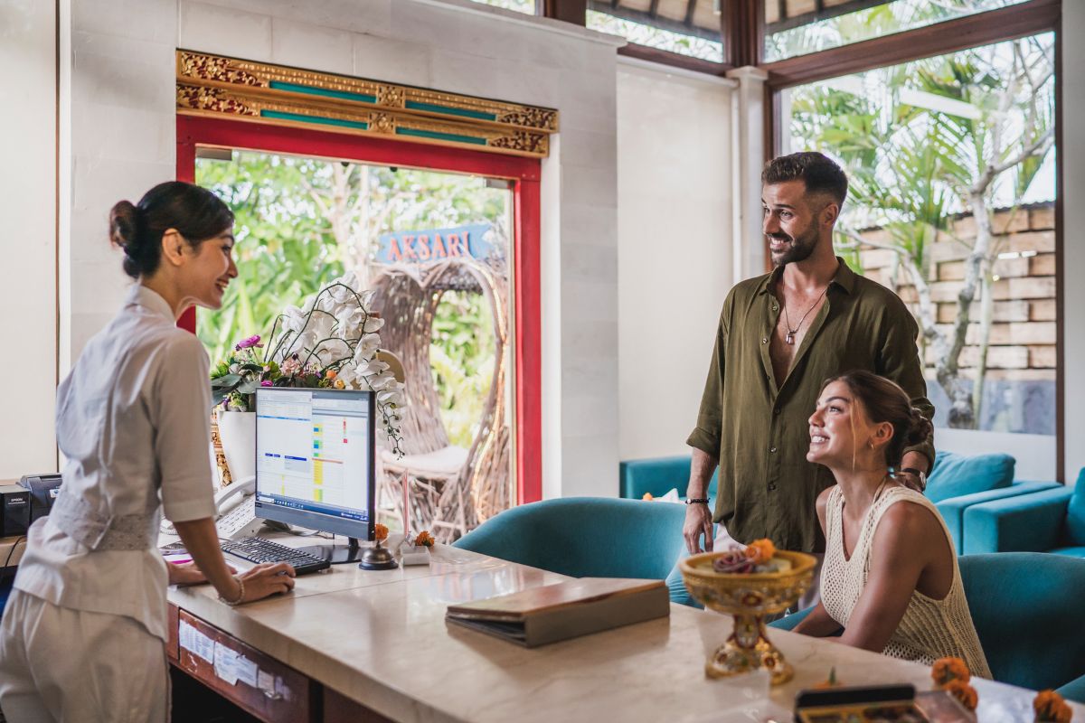 staf hotel yang sedang melayani tamu dengan ramah