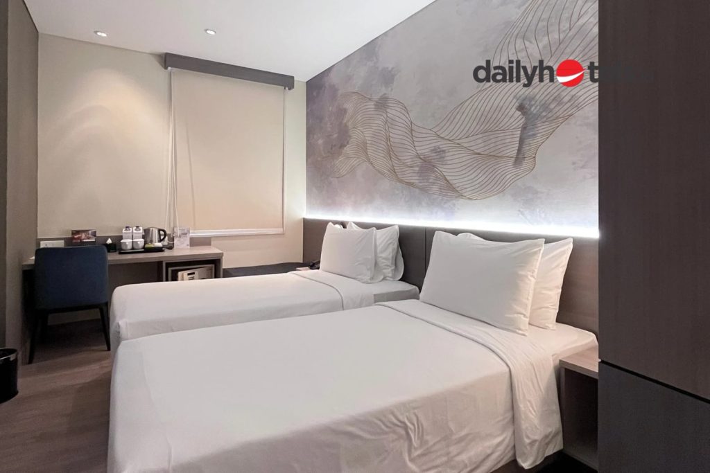 A clean and modern hotel room interior of an Express Room, featuring a comfortable bed with crisp white linens, minimalist furniture, and bright ambient lighting at Swiss-Belexpress Jemursari Surabaya.