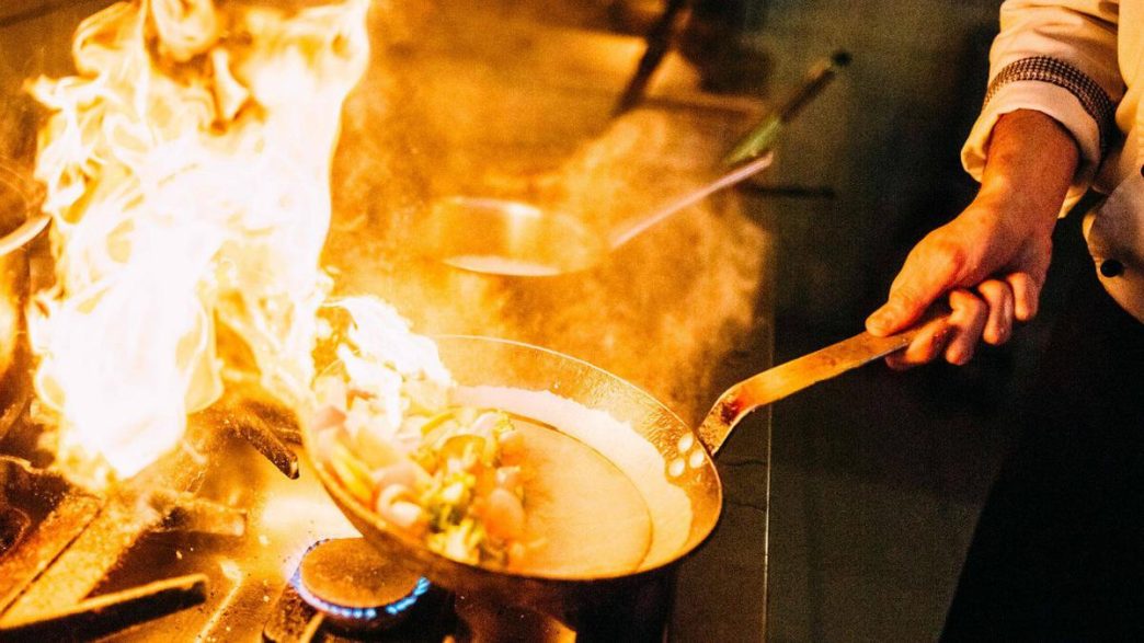 Strategi chef hotel saat memasak hidangan di dapur profesional.