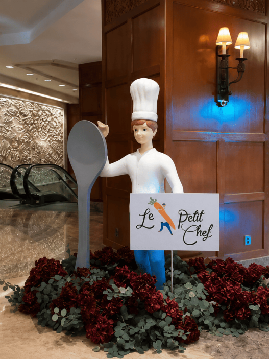Dekorasi Le Petit Chef dengan patung koki dan sendok raksasa di lobi hotel