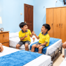 Anak-anak bersama pendamping berada di kamar YPKAI dengan tempat tidur dan perlengkapan kamar yang tertata