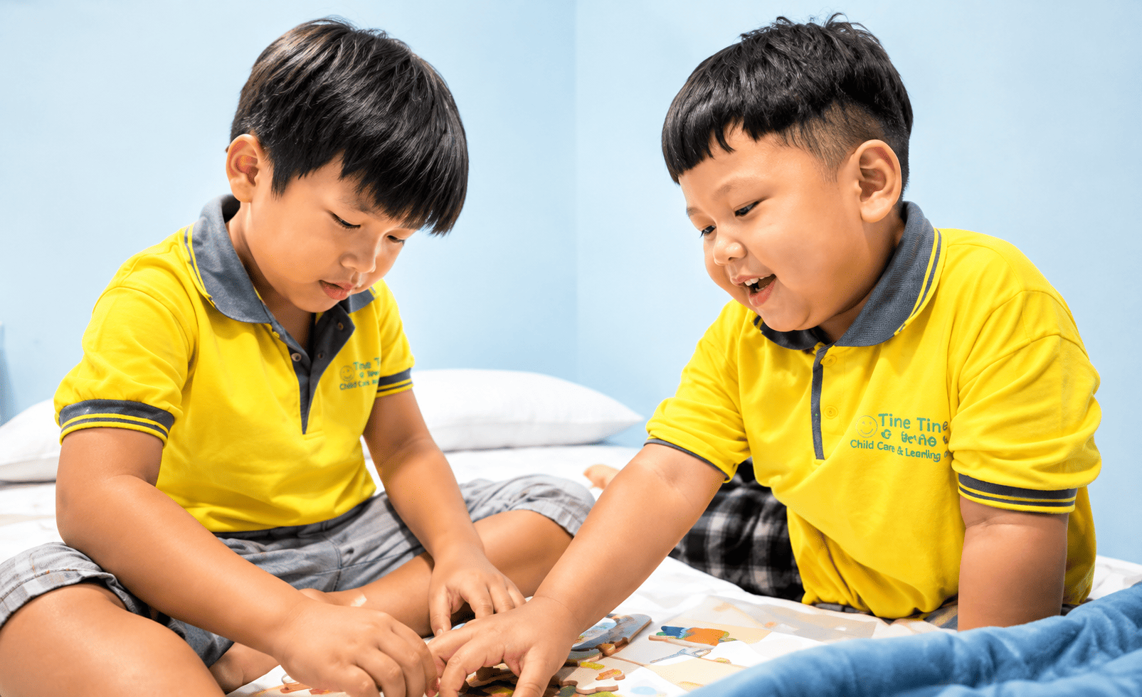 Dua anak bermain bersama di atas tempat tidur dalam kamar YPKAI Surabaya