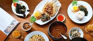 Aneka hidangan Thailand dengan ikan goreng, nasi, sayuran, kari, sambal, dan makanan pendamping di meja restoran