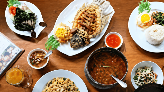 Aneka hidangan Thailand dengan ikan goreng, nasi, sayuran, kari, sambal, dan makanan pendamping di meja restoran