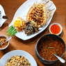 Aneka hidangan Thailand dengan ikan goreng, nasi, sayuran, kari, sambal, dan makanan pendamping di meja restoran