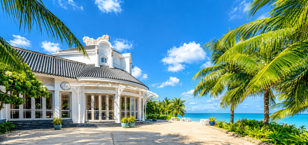 JW Marriott Phu Quoc Emerald Bay Resort & Spa, resor tepi pantai dengan bangunan putih bergaya klasik, dikelilingi pohon kelapa dan pemandangan laut biru di Phu Quoc, Vietnam.