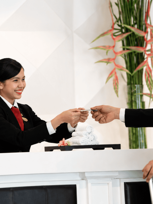 Proses check-in hotel saat staf Front Office menyerahkan kartu kamar kepada tamu
