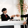 Proses check-in hotel saat staf Front Office menyerahkan kartu kamar kepada tamu