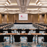 Meeting room hotel dengan proyektor dan tata kursi U-shape untuk rapat bisnis