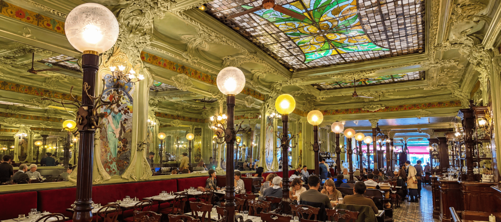 Interior Bouillon Julien di Paris dengan panel kaca patri, ornamen Art Nouveau, lampu dekoratif, dan deretan meja makan klasik