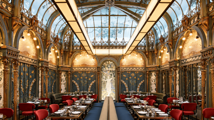 Interior Beefbar Paris dengan atrium kaca, dekorasi Art Nouveau, ornamen artistik, dan kursi makan berwarna merah