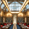 Interior Beefbar Paris dengan atrium kaca, dekorasi Art Nouveau, ornamen artistik, dan kursi makan berwarna merah