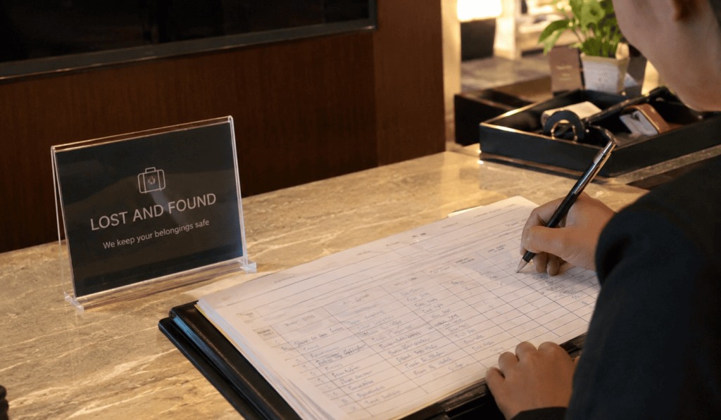 Staf hotel mencatat barang temuan dalam buku log lost and found untuk memastikan pendataan yang tertib