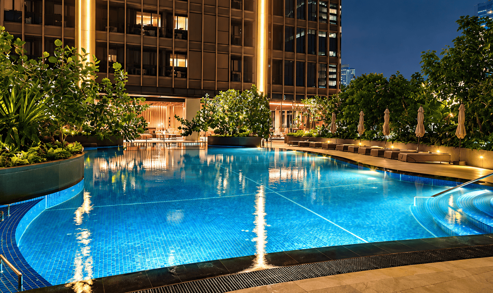Kolam renang outdoor Swissôtel Living Jakarta dengan area hijau.