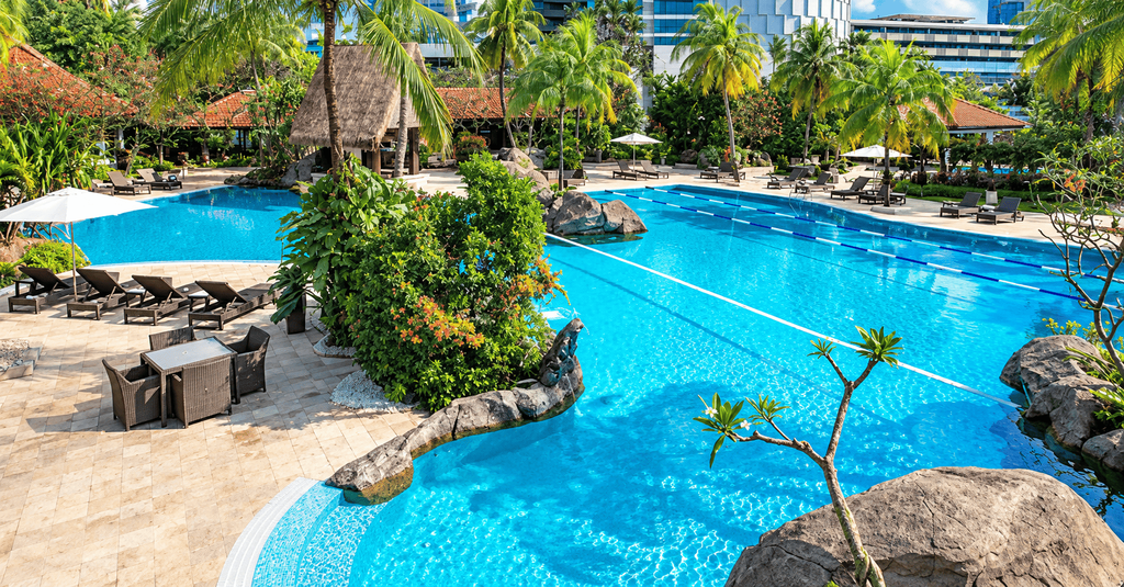 Kolam renang outdoor Grand Hyatt Jakarta dengan suasana tropis, pepohonan palem, dan area bersantai.