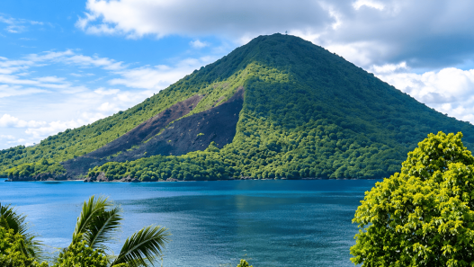 Pemandangan alam Banda Neira dengan gunung berapi hijau dan laut biru yang jernih.