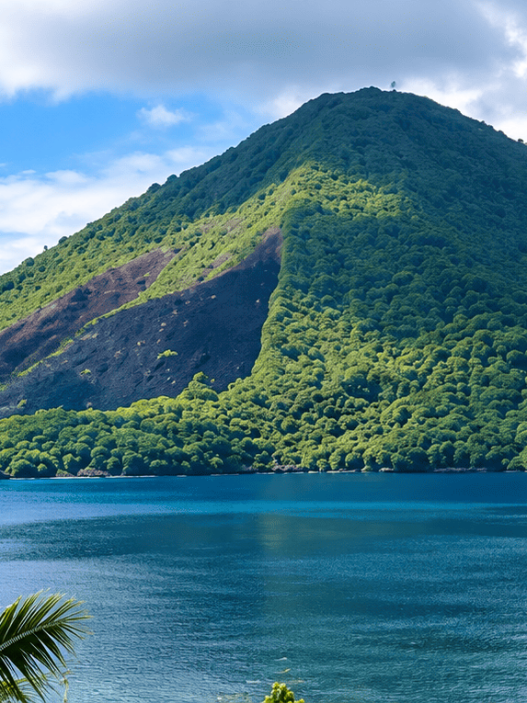 Pemandangan alam Banda Neira dengan gunung berapi hijau dan laut biru yang jernih.