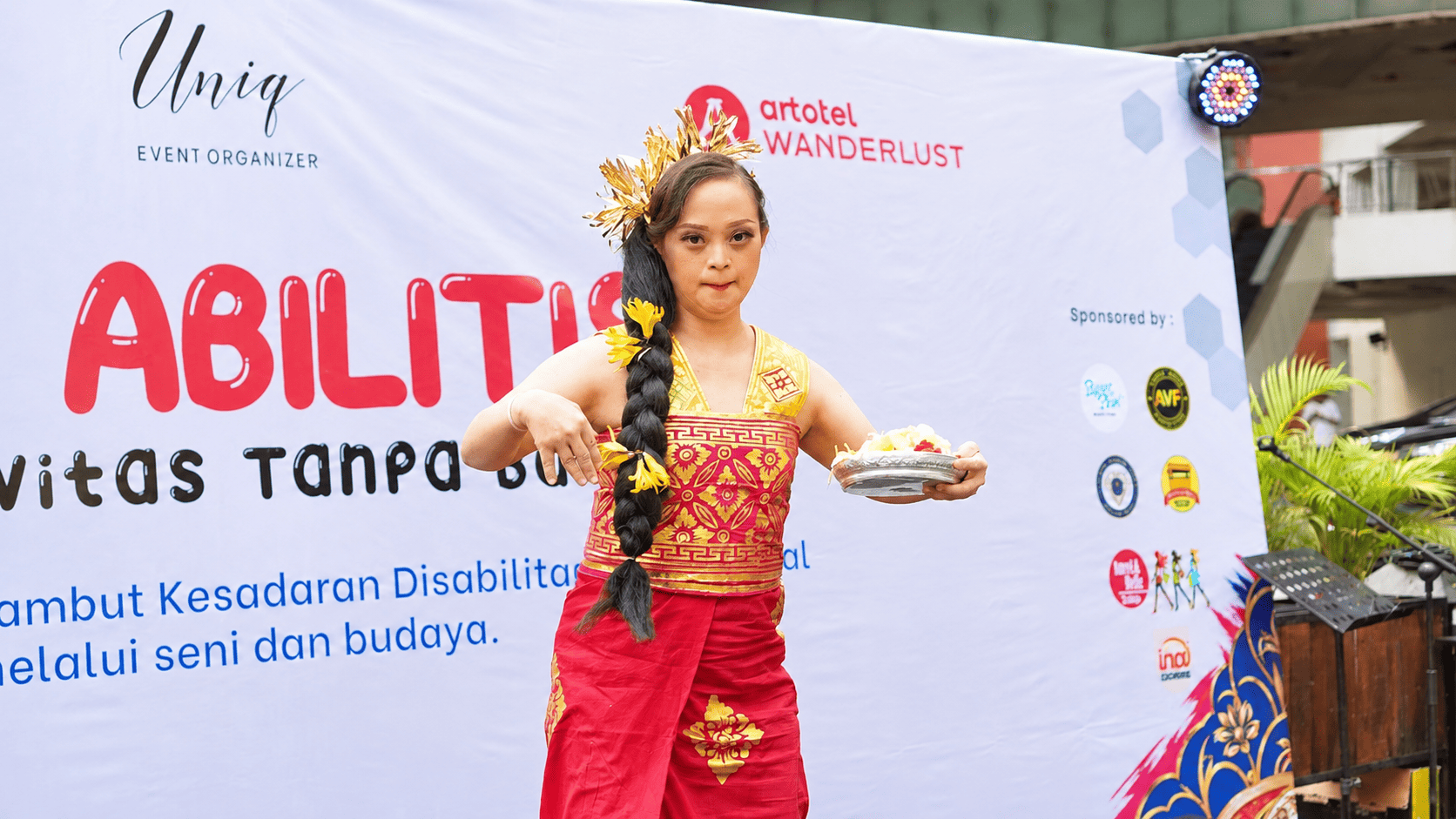 Seorang peserta menampilkan tarian tradisional dengan busana merah dan emas dalam acara Uniq Abilities – Kreativitas Tanpa Batas di ARTOTEL Grand Prima Surabaya.