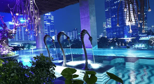 Kolam renang rooftop The Orient Jakarta dengan pemandangan gedung-gedung Jakarta pada malam hari.