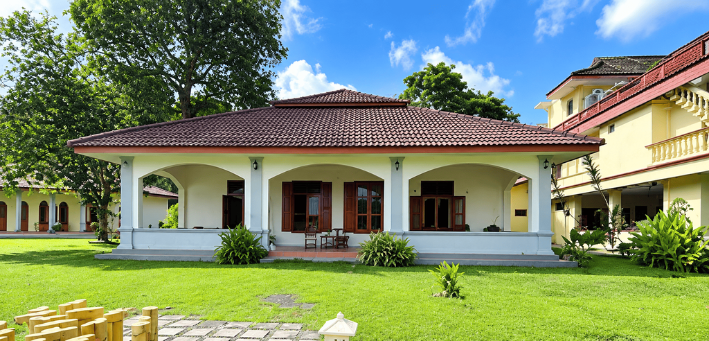 Tampilan eksterior The Maulana Hotel dengan halaman hijau dan bangunan bergaya klasik.