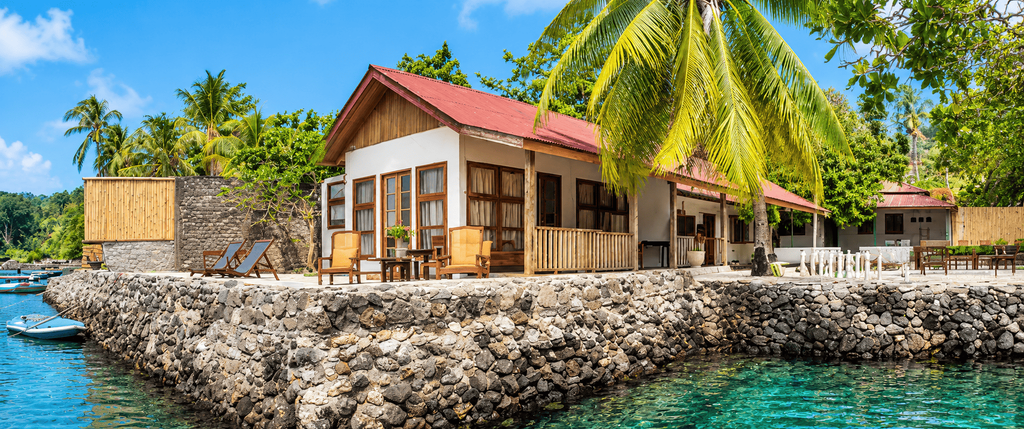 Eksterior The Nutmeg Tree Hotel & Dive dengan bungalow tepi laut, pohon kelapa, dan pemandangan laut tropis.