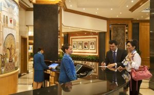 Proses check-in tamu di meja resepsionis hotel