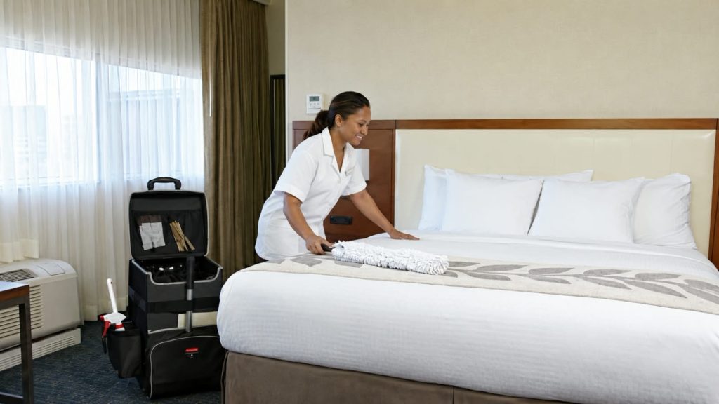 Staff housekeeping merapikan tempat tidur hotel